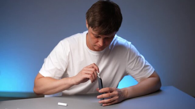 Focused technician male cleaning smartphone charging port using specialized tool, maintaining device hygiene and ensuring optimal performance and longevity for portable technology at workshop.