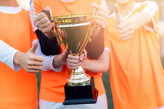Young womens football team celebrates victory with trophy