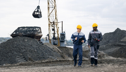 Male engineers surveying in sand quarry and ore mining site