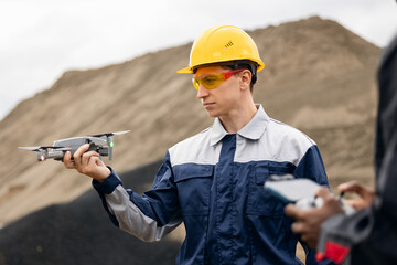 Worker Using uav drones for monitoring mining operations by surveying engineer
