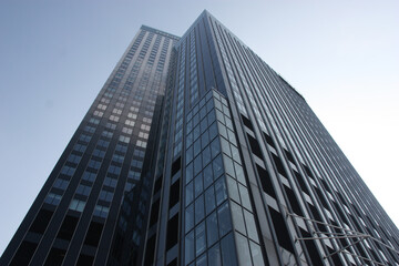 Editorial upward view of a modern skyscraper in Rotterdam, Netherlands, showing glass and steel architecture against a clear blue sky.