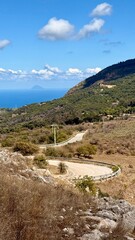 Mountainous central Sicilian landscape near Campofelice di Roccella, Italy, featuring rolling hills, distant Tyrrhenian Sea views, and the volcanic Islands on the horizon under