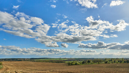 Obraz premium clouds over an agricultural field. A spring landscape with a forest, an empty field and clouds. A field after harvesting wheat.