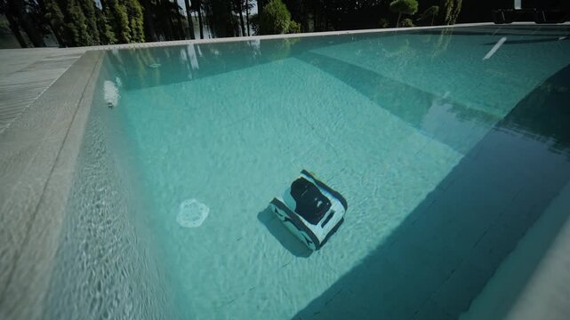 Robotic pool cleaner moving along the edge of a clear blue swimming pool