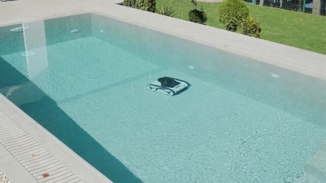 Robotic pool cleaner moving along the edge of a clear blue swimming pool