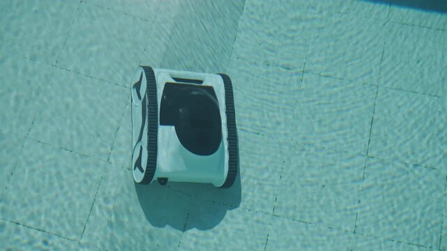 Robotic cleaner vacuuming the bottom of a turquoise pool