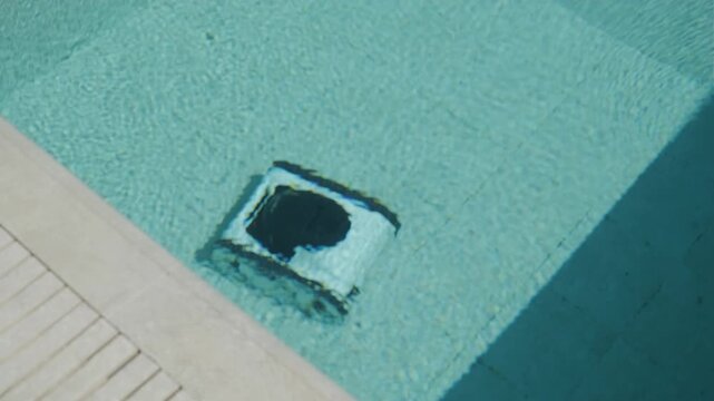 Robotic pool cleaner working near the corner of the swimming pool