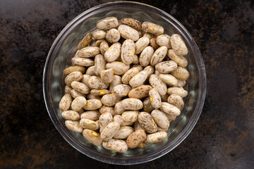 Pinto beans in a glass container in a black pan surface