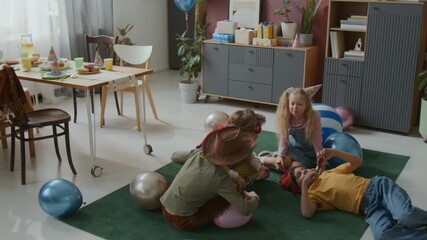 High angle shot of group of young children in costumes playing on green carpet during lively birthday party - Powered by Adobe