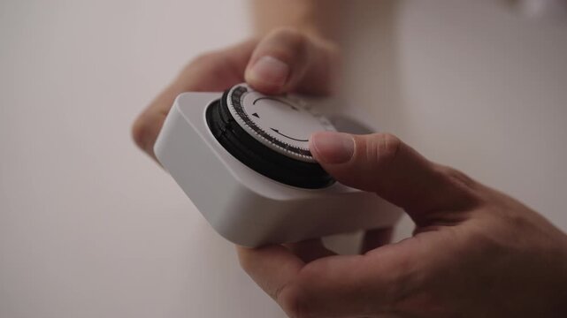 Man adjusting timer switch, ensuring precise control over electrical devices for effective time management and energy efficiency in various home and industrial applications, close-up, slow motion.