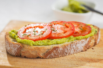 A slice of bread with avocado and tomato decorated with parsley