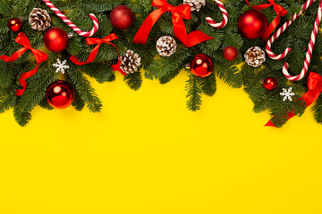 Christmas tree branches with festive decoration on color background, top view