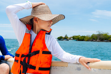 Colombian child adjusting traditional hat on boat with copy space in Mucura Island, Colombian Caribbean