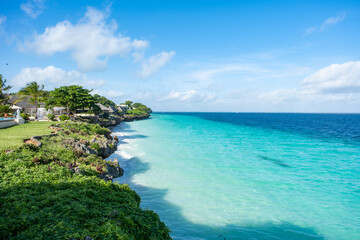 Fototapeta premium Idyllic tropical beach in Nungwi, Zanzibar, with white sand, turquoise waters, and palm trees under a clear blue sky. Perfect paradise escape in East Africa.