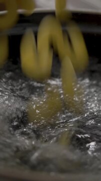 Water rapidly boils in pot on stove. Short pasta poured in, swirling through heat. Key moment in preparing satisfying meals. Ideal for quick, delicious dinner options using simple ingredients