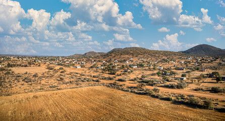 aerial view, African village in Botswana, hills and mountain range, dry terrain and agriculture