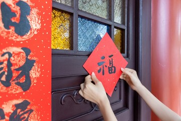 Festive New Year Decorations Affixed to Brown Door with Red Paper Cutout and Calligraphy in...