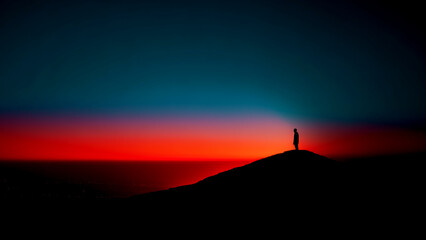 Fototapeta premium 夕暮れの山の頂上に立つ人のシルエット