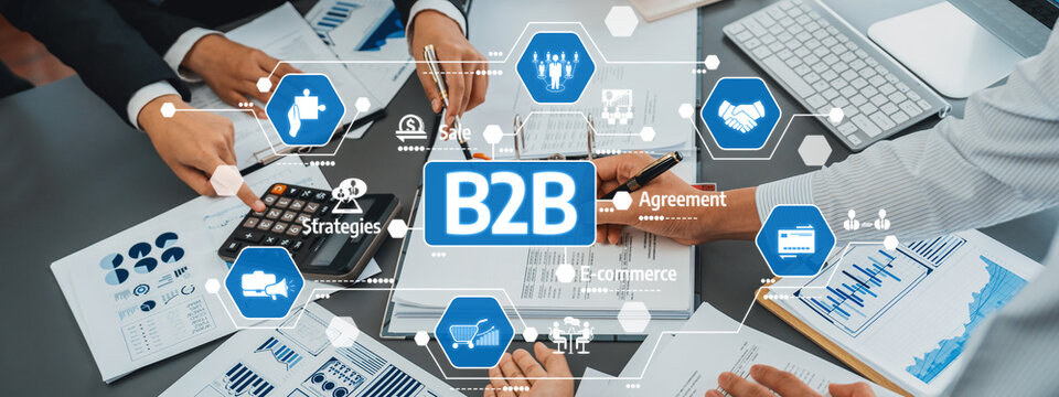 Business professionals engage in collaborative efforts to develop B2B strategies using documents, charts, and digital tools in a dynamic workplace setting. Amity