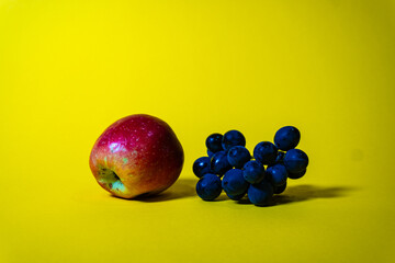 Still life with a bunch of dark grapes in a clay jug on a bright yellow background. Minimalist composition for advertising and design.