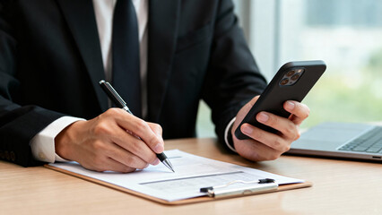 Businessman using stylus on text holding smartphone, representing multitasking, digital workflow, and smart office solutions. mobile management, e-signature, and business apps.