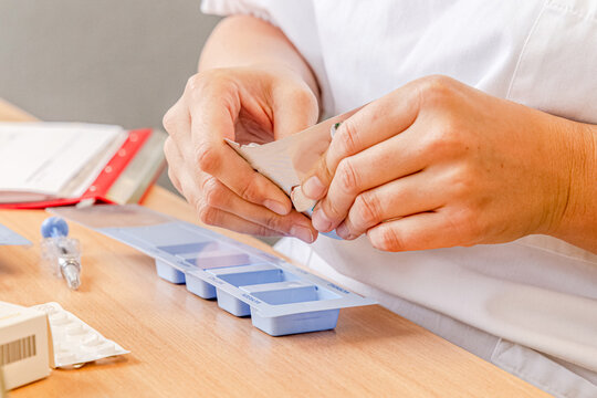 Nurse preparing medication in a weekly pill organizer, professional medical care and accuracy in nursing