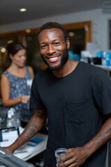 Obraz premium A cheerful bearded man stands behind a work counter, engaging warmly with customers and showcasing various beauty products, effectively creating an inviting shopping experience.