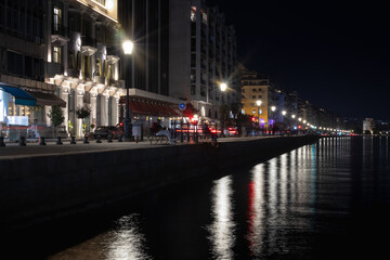 night cityscape by the water, a long exposure captures the reflections of streetlights and...
