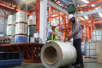African american technician industrial worker and asian engineer inspecting aluminum metal sheet fabricating roll check stock materials in steel coil storage area, rolls metal sheet high quality.