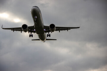 Airplane flying through cloudy sky, showcasing powerful engines and landing gear, capturing the essence of aviation and travel in a dramatic atmosphere