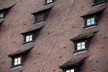 Architectural detail of a sloped roof featuring multiple windows and textured tiles, showcasing traditional craftsmanship and design elements in a unique building structure