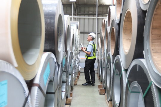 Industrial Engineer in Hard Hats Work at the Heavy Industry Metal Sheet Manufacturing Factory. Factory worker indoors in metal sheet factory. Man working in an industrial factory.