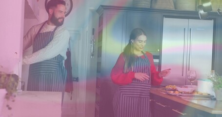 Smiling man and woman in dark striped aprons chopping vegetables in home kitchen, with wine glass