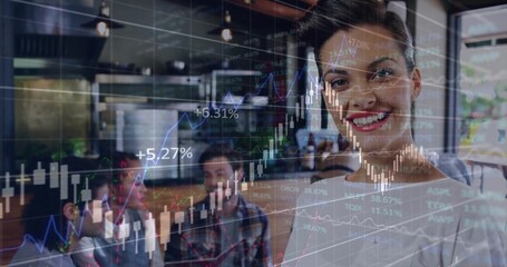 Smiling woman presenting financial charts in kitchen, with colleagues conversing by wooden table