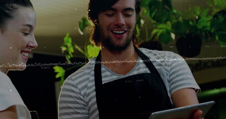 Holding tablet computer, barista showing data overlay at cafe counter, with hanging potted plants