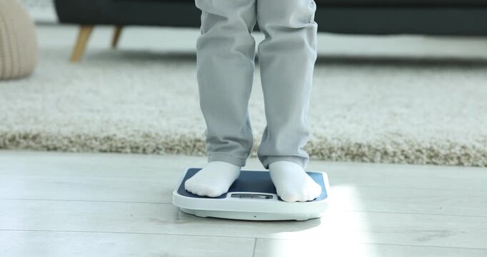 Little boy measuring his weight on scales at home, closeup