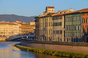 View of the Arno River with the Ponte di Mezzo bridge and pastel-colored buildings in the historic center of Pisa, Italy