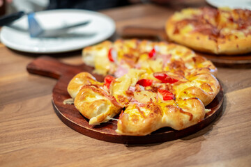 Hot baked cheese pizza with ham, pineapple, and bell pepper served on a wooden tray in a restaurant. Freshly cooked delicious pizza ideal for food, lunch, dinner, or Italian cuisine concepts.