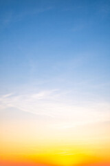 Sunset or sunrise sky with a vibrant gradient of orange, gold, and soft blue. Clear atmosphere with wispy clouds. Peaceful, natural light background. hope, freedom, new day Concepts, Vertical