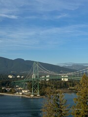 Beautiful view of Lions Gate Bridge stretching across Burrard Inlet with mountain and blue sky background in Vancouver, Canada.
