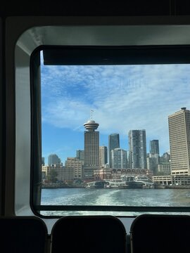 Vancouver city skyline view framed by the seabus window under blue sky.