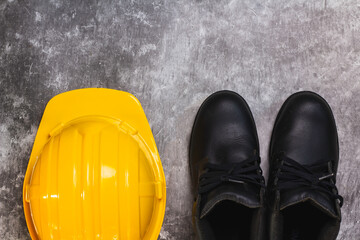 Close-up top view of protective equipment on a construction site yellow hard hat and safety shoes.
