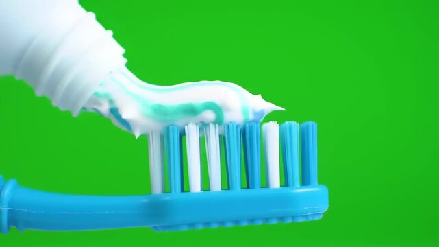 Close-up of Toothpaste Being Squeezed onto a Blue Toothbrush Against a Green Screen Background