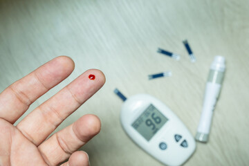 Woman's hands checking diabetes and hyperglycemia with digital blood sugar meter. Healthcare and...