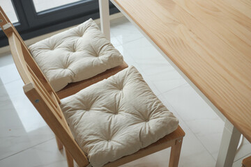 Cozy wooden chairs with cushions at a bright table