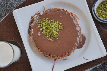 kunafe chocolate dessert with pistachio topping and milk