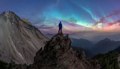Person Standing On A Mountain Peak Under Northern Lights And Starry Sky © edb3_16