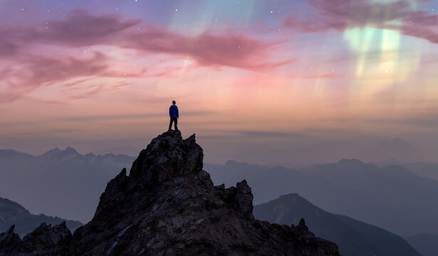 Hiker Standing On A Jagged Peak Beneath A Colorful Sunset And Aurora Sky - Powered by Adobe