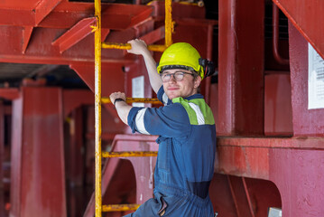 Portrait of the young marine engineer officer climbing a ladder on board of the large cargo...