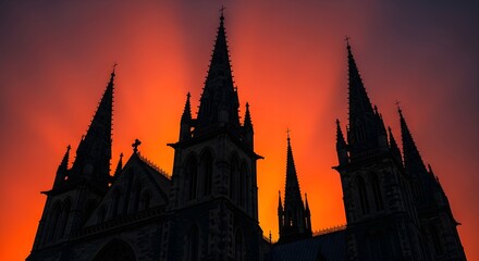 Fototapeta premium A photo of classic church architecture with dramatic lighting, showcasing a silhouette of spires against a vibrant orange and purple sky at sunset.